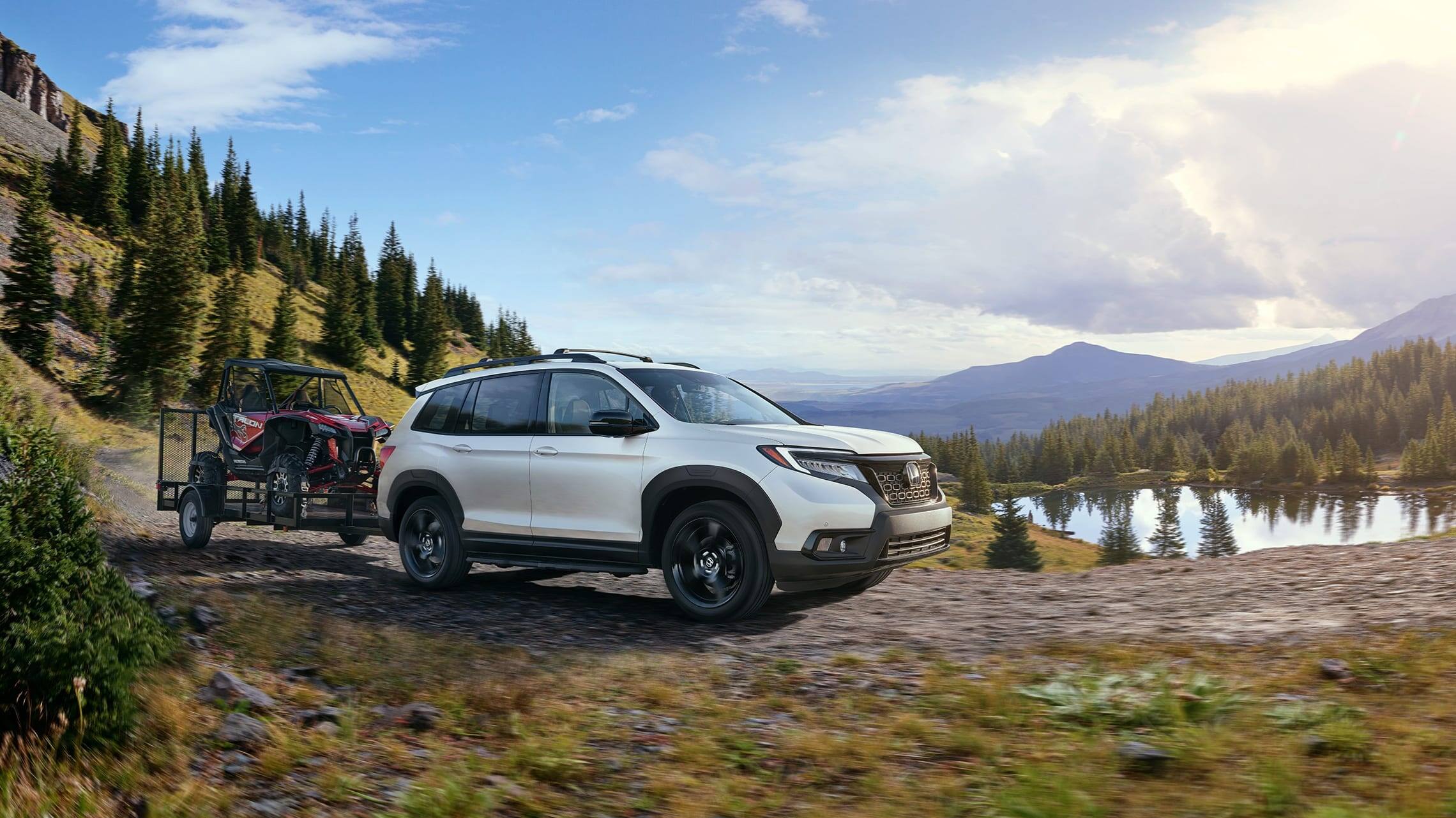 Passenger-side front 7/8 view of 2019 Honda Passport Elite in White Diamond Pearl with accessory tow hitch.
